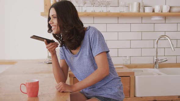 Woman talking on smart phone in the kitchen