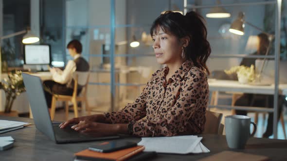 Hispanic Businesswoman Using on Laptop in Office at Night