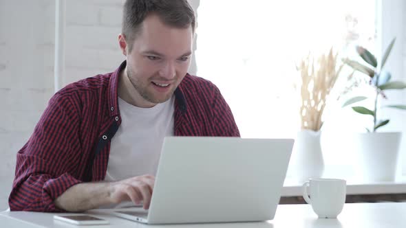 Excited Young Man Celebrating Success Working on Laptop