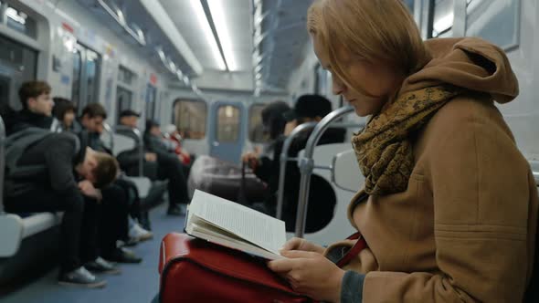 Young woman reading a book in subway