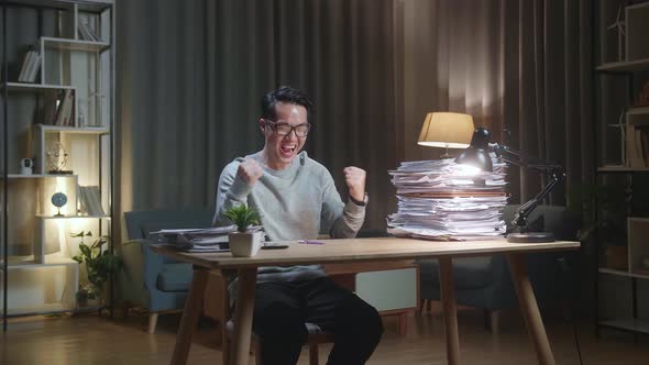 Happy Asian Man Celebrating Finishing Working With Documents At Home