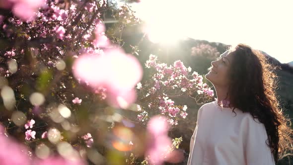 A Young Woman Enjoys a Blooming Spring Garden at Sunset in the Mountains