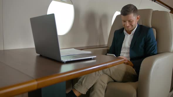 Business Man Chatting Sitting in Comfortable Armchair in Private Jet Cabin