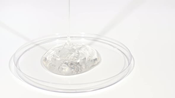 Transparent Cosmetic Gel Fluid Dripping Into the Glass Bowl of Petri