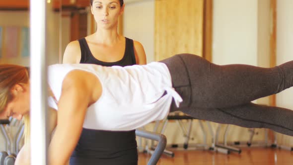 Female trainer assisting woman with exercise