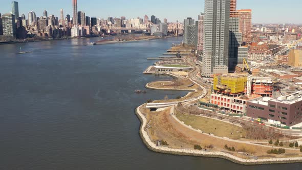 A high angle view looking north over the East River on a sunny day. The drone camera truck right and