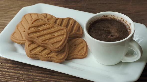 Cup of coffee with cookies on a wooden table.