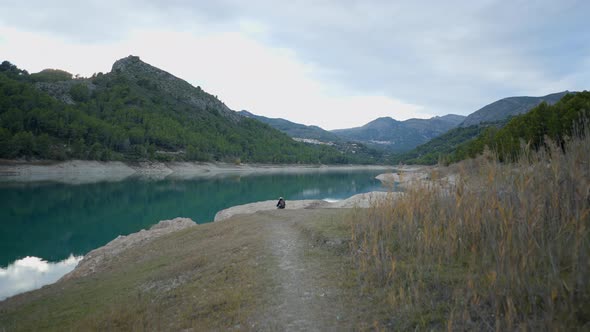 POV of Walking Towards Other Person By Lake and Forested Hills Spain