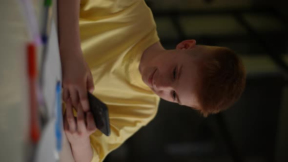 Vertical Shot of Happy Child Boy with Freckles Playing Online Games on Smartphone Spending Free Time