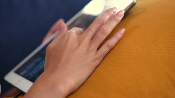 Close Up hand of Asian young woman while on sofa using a tablet.