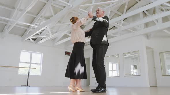 Caucasian senior couple spending time together in a ballroom and dancing