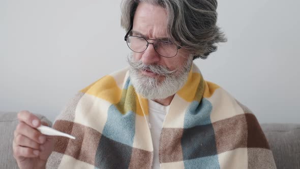 Closeup of Mature Man in Glasses and Blanket Measuring Temperature at Home