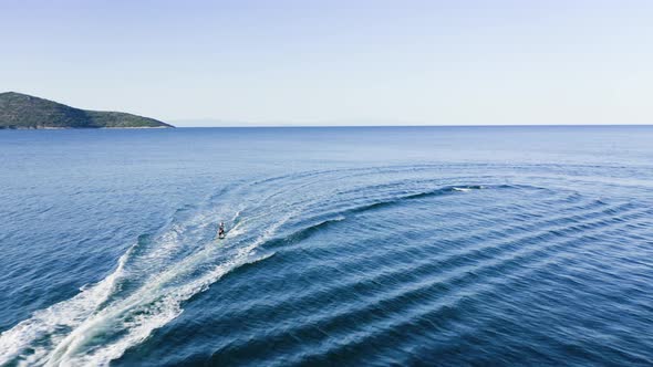 Drone view of kid doing water ski in the sea.