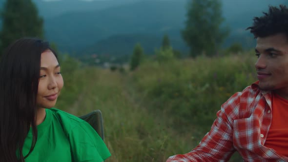 Romantic Multiethnic Couple Tourists Relaxing with Hot Drinks During Mountain Hiking