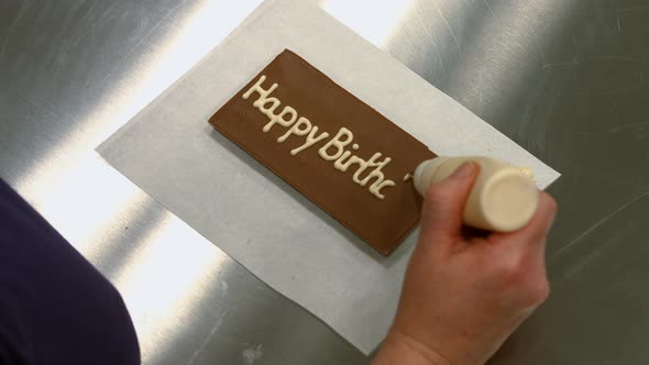 Worker writing happy birthday on a chocolate plaque