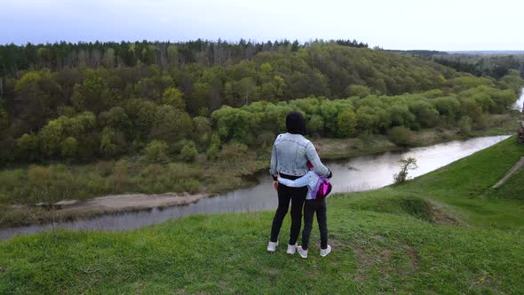 Mother and daughter enjoys the view on the coast Sluch river hills