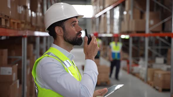 Storehouse Manager Talking on Radio During Work