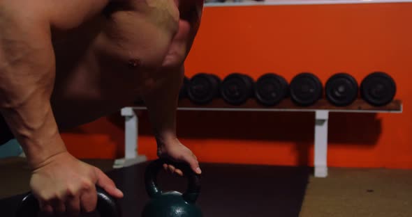 Muscular man performing push-up exercise with kettlebell