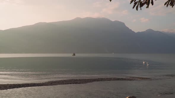 Mystic light of sunrise on lone mountain, golden morning, empty Lake Garda shore