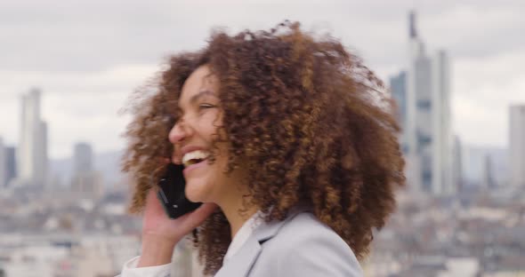 Businesswoman talking on the phone standing on windy roof top terrace