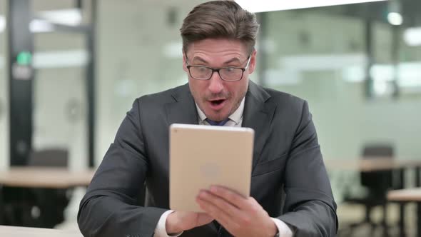 Middle Aged Businessman Celebrating Success on Tablet