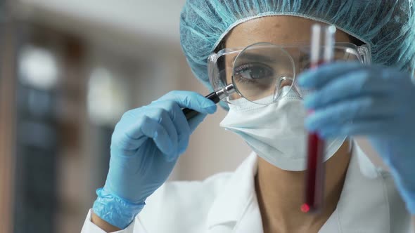 Female Medical Worker Looking at Blood Test Through Magnifying Glass, Analysis