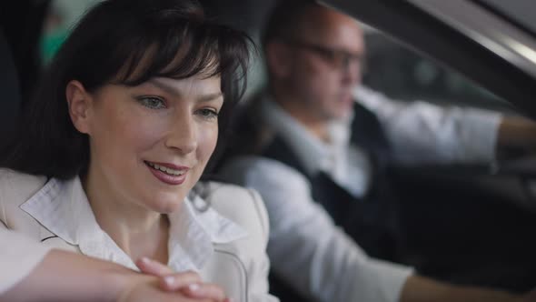 Charming Satisfied Wealthy Woman Admiring Luxurious Car Interiors Sitting with Man in Vehicle in
