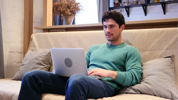 Man Celebrating Success While Working on Laptop Sitting on Couch