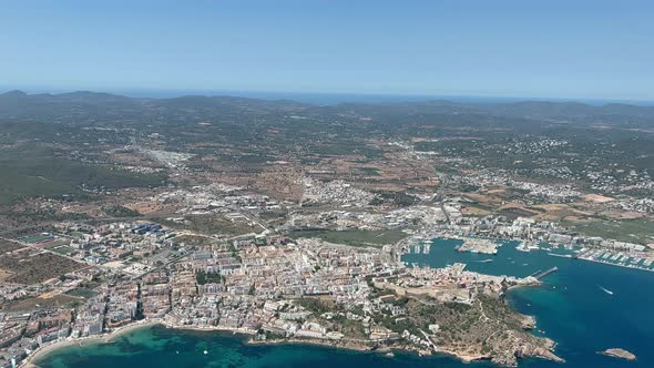 Aerial view from a jet cockpit of Ibiza city and harbor in a summer afternoon. View of the castle an