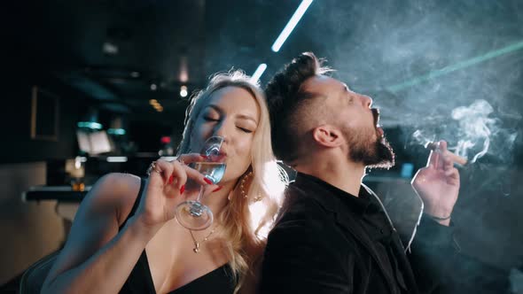 Portrait of an Attractive Business Man and Blonde Woman. Bearded Man with a Cigar in a Dark Room