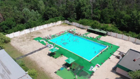 Flight Over the Blue Pool with People on Vacation. Aerial View on Clean Swimming Pool