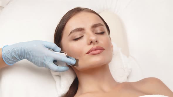 Beautician Arm Using Cosmetology Apparat on Female Face