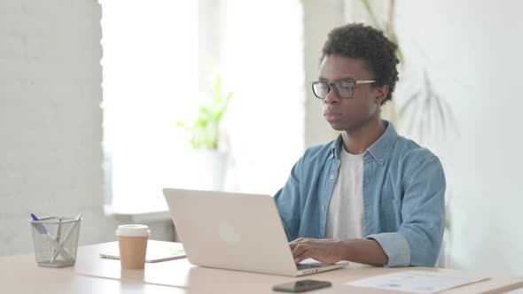 Young African Man Shaking Head in Rejection While Using Laptop in Office