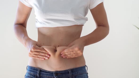 Young Woman Holding and Squeezing Abdominal Fat. Obesity, Unhealthy Lifestyle