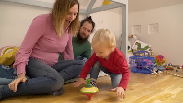 Family playing with spinning toy in children room during the morning.