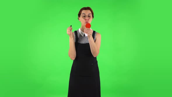 Funny Girl in Round Glasses Is Painting Her Lips Looking in Red Mirror, Green Screen