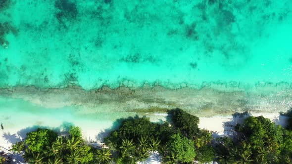 Daytime overhead island view of a sunshine white sandy paradise beach and aqua blue water background