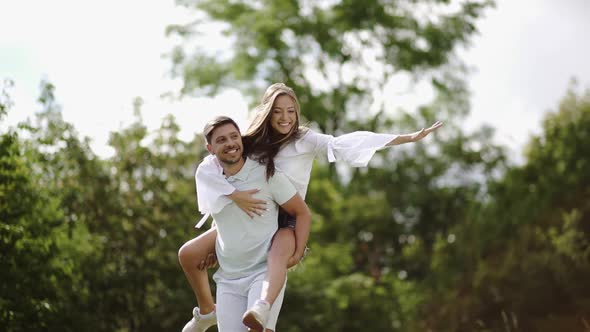 Beautiful Couple Having Fun In Nature. Portrait Of Handsome Man Carrying Woman.