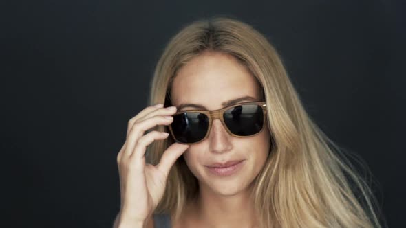 Young woman lowering sunglasses and winking at camera