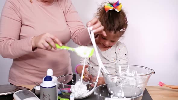 Step by step. Mother and daughter making colorful fluffy slime.