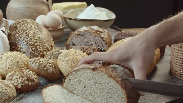 Hands Cutting the Baked Dutch Bread on the Table