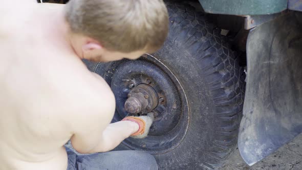 Man Installs a Wheel on an Old Car Closeup