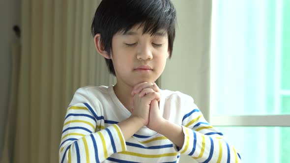 Cute Asian Child Boy Praying With Eyes Closed In The Morning