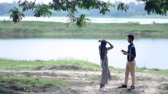 Stylish romantic Asian couple having fun and playing with each other near a lake in forest or nature