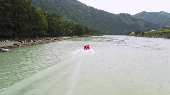 A Red Boat with People Floats on a Gray River