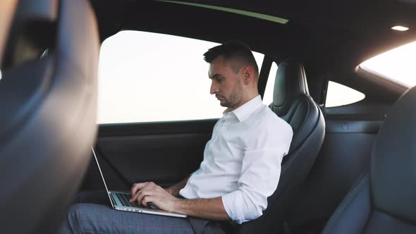 Businessman Working on Laptop Computer in the Back Seat of a Car