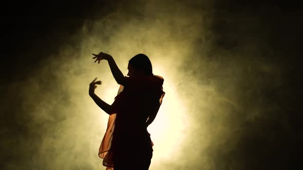 Silhouette a Young Girl Dancer in a Red Sari in an Indian Folk Dance on Stage in a Dark Studio with