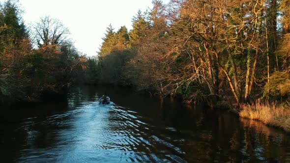 Aerial shot lake boat travelling down river in Autumn