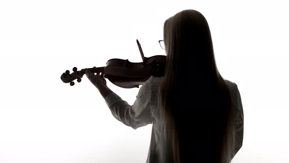 Woman violinist plays violin, the view from behind on white studio background.