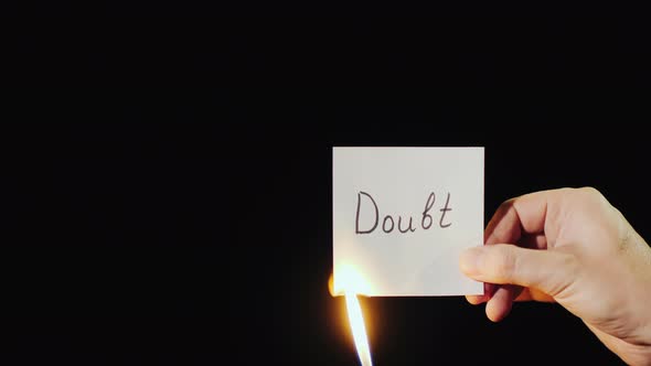 Man Burns a Paper with the Inscription Doubt